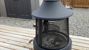 Una estufa de leña con chimenea, ubicada en una terraza de madera.