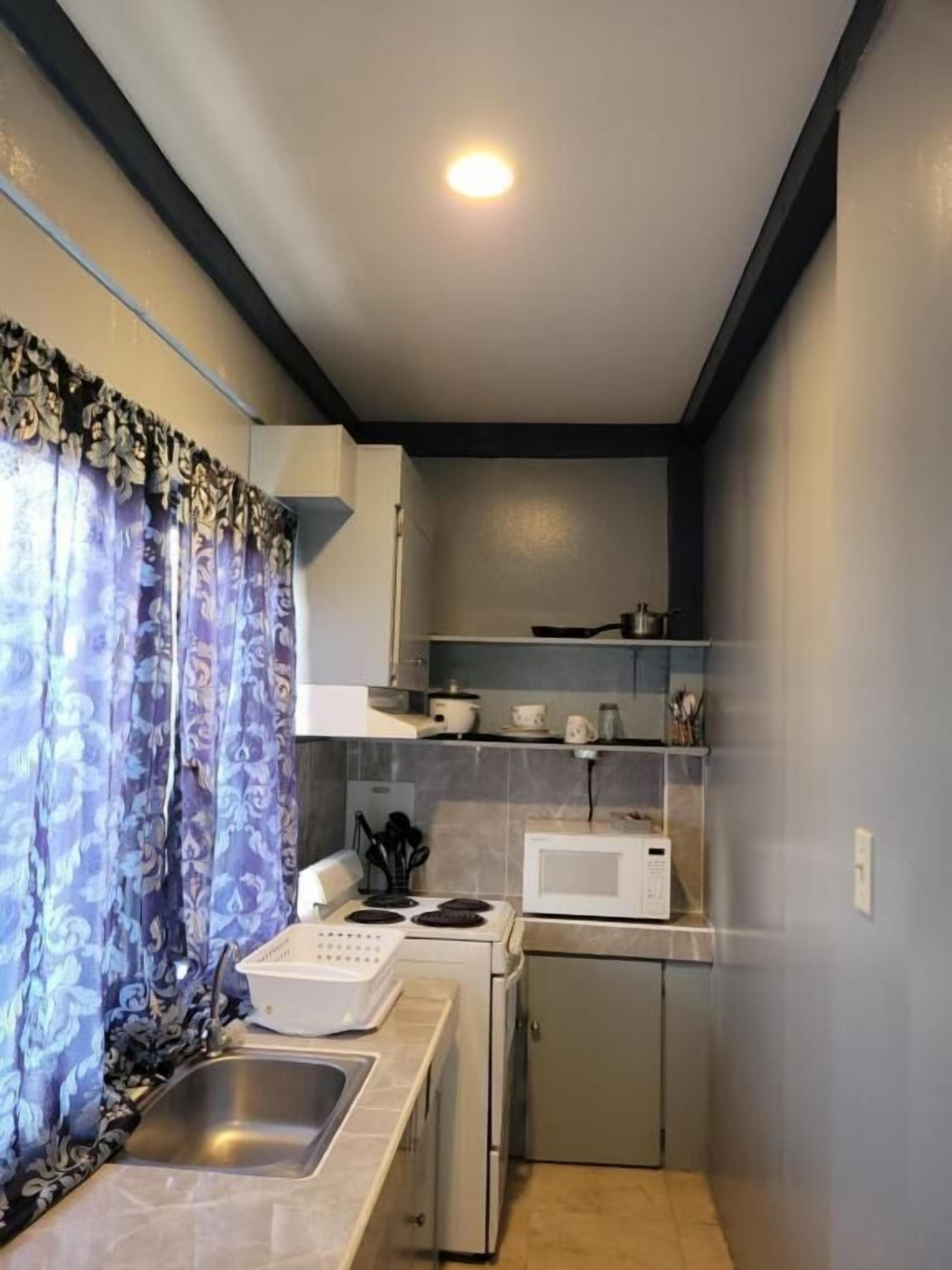 A compact kitchen with a sink, stove, microwave, and cabinets.