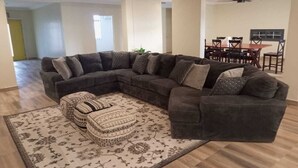 A living room with a sectional sofa, ottomans, and a patterned rug.