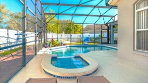 Una piscina exterior cubierta con jacuzzi, rodeada por una zona de patio con sillas.