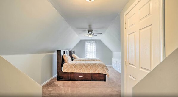 Une chambre avec un lit en bois foncé, un ventilateur de plafond et une porte blanche.