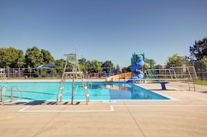 A swimming pool with a slide and a lifeguard tower.