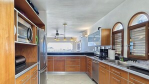 Una cocina con armarios de madera, electrodomésticos de acero inoxidable y vistas al exterior.