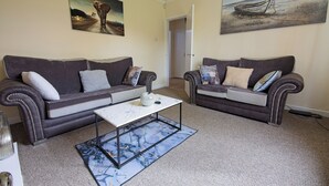 A living room with two dark brown sofas, a white coffee table, and a marble-patterned rug. - Stylish Five Star Rated Apartment (Manchester)