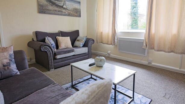 A living room with a sofa, a coffee table, and a painting on the wall. - Stylish Five Star Rated Apartment (Manchester)