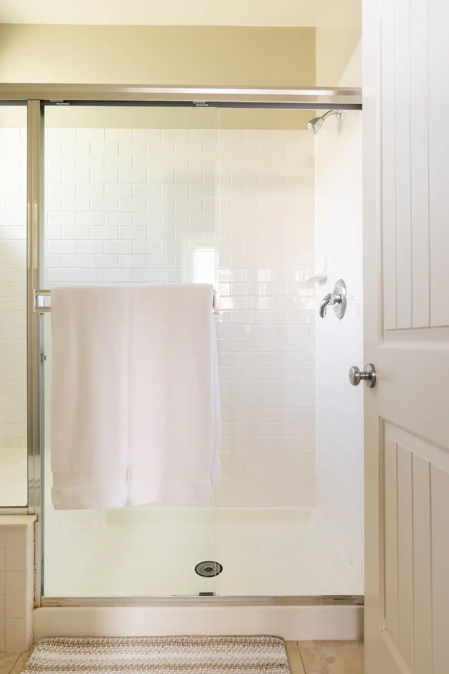 A glass-enclosed shower with a white towel hanging on the door handle.