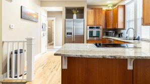 A modern kitchen with wooden cabinets, stainless steel appliances, and a granite countertop.