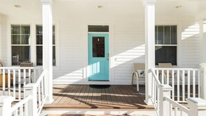 A white house with a turquoise door, white railings, and a number 11761 on the front.