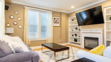 TV connectée, cheminée, livres, écrans d'ordinateur