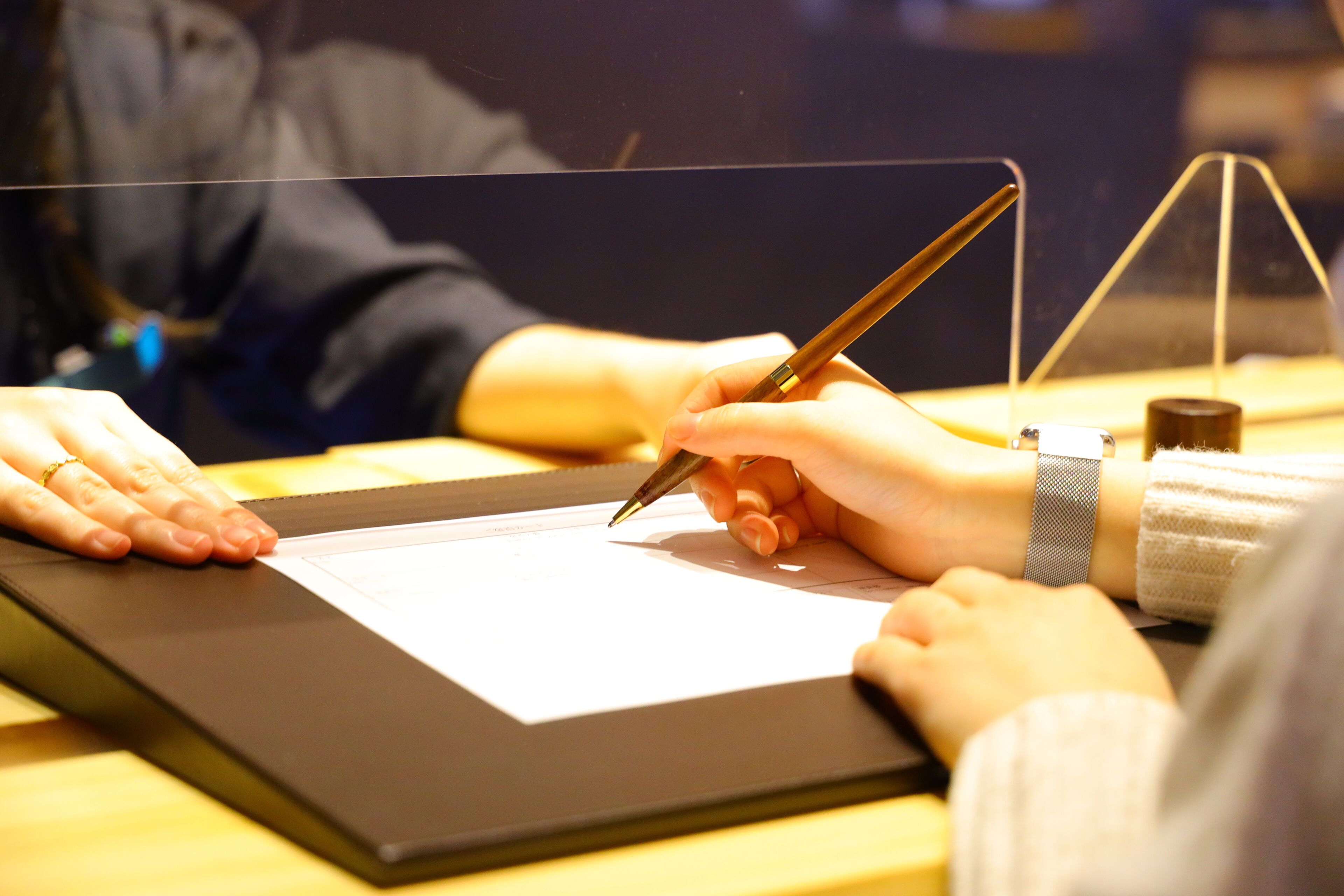 A person using a stylus on a tablet, with a pen in hand, and a watch on their wrist.
