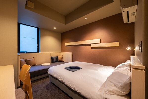 Una habitación de hotel moderna con una cama, un escritorio y un ventanal.