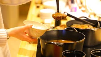 A person holding a bowl, with a pot and a ladle in the foreground.