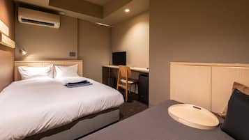 A hotel room with a bed, a desk, a chair, and an air conditioning unit.