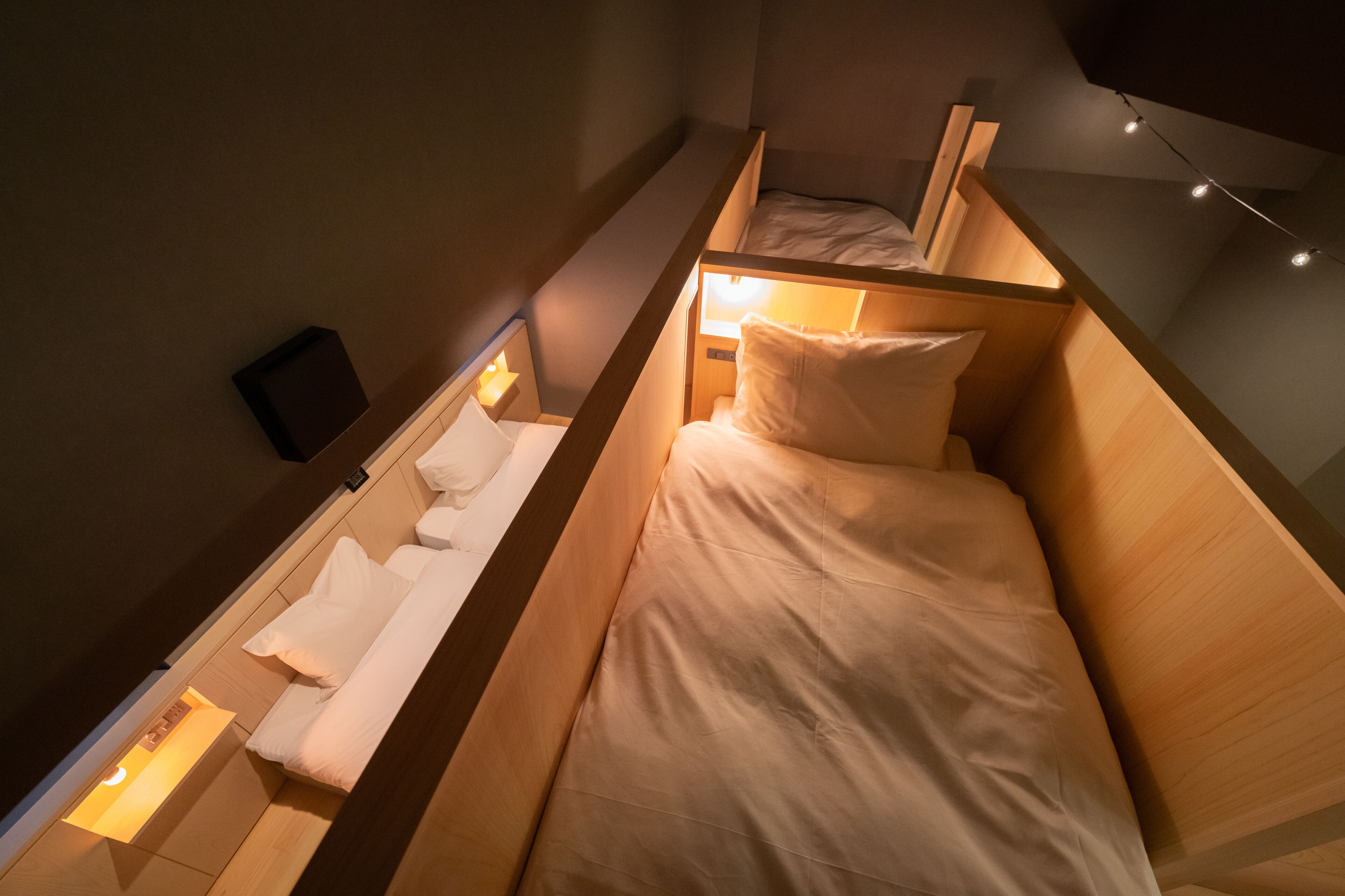 A compact, modern room with a bunk bed and a single bed, both with white bedding.
