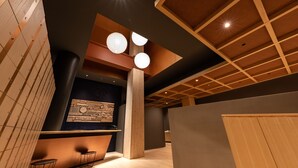 A modern interior with wooden paneling, a reception desk, and pendant lighting. - OnnNakatsugawa (Nakatsugawa)