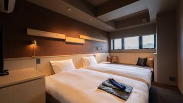 A hotel room with two beds, a desk, a lamp, and a window with a view.