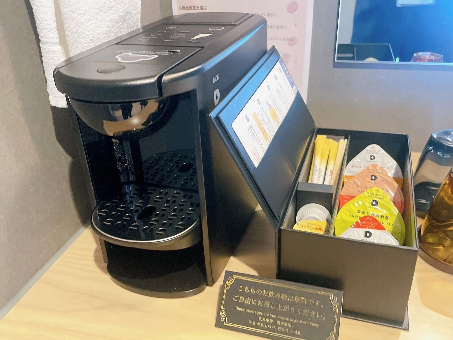 A coffee machine with a display screen and a box of tea and coffee pods.