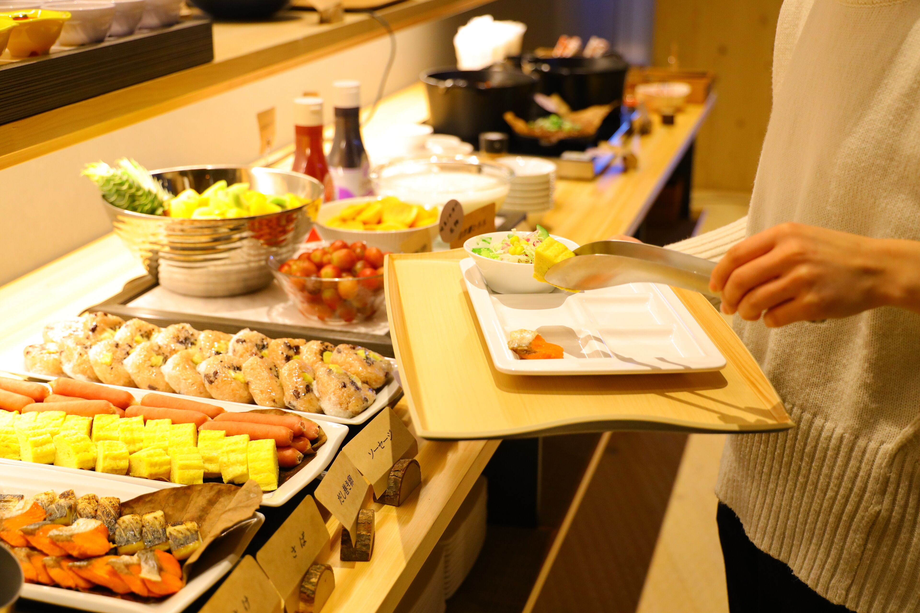 A buffet with various food items including sushi, vegetables, and hot dogs.