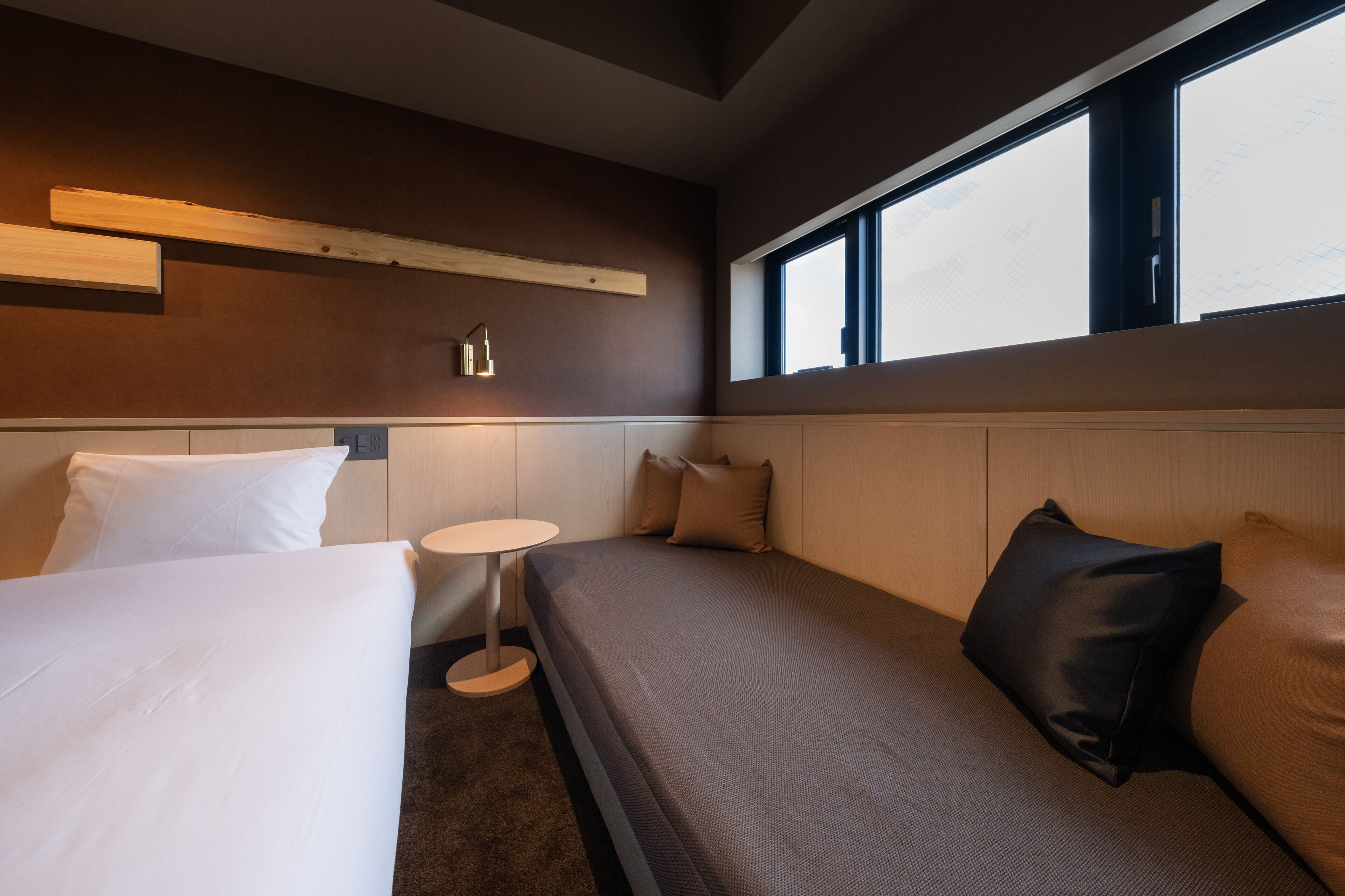 A hotel room with a bed, a small round table, and a window with a view.