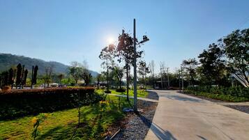 A paved pathway in a park with trees and a small structure.