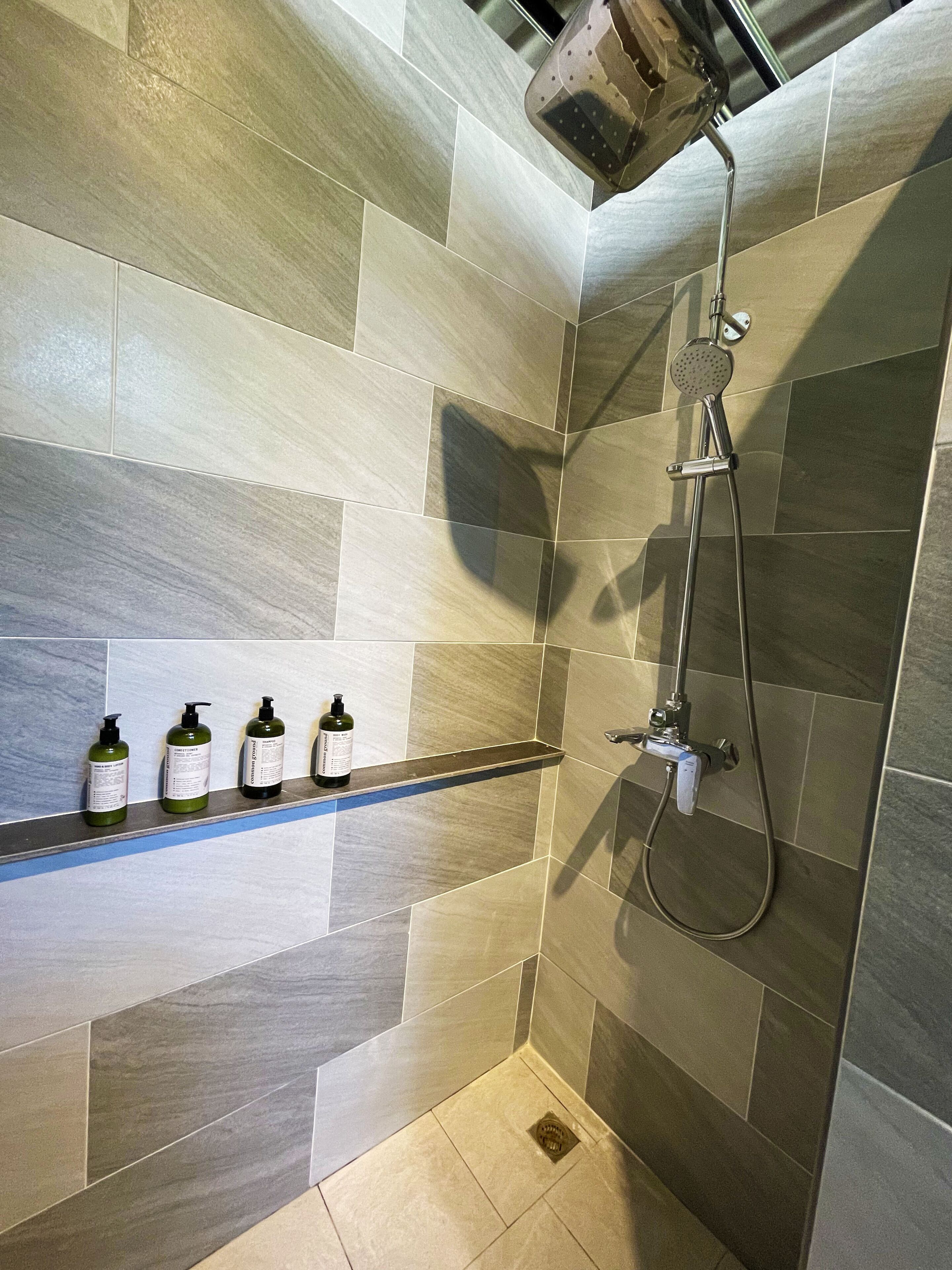 Un espace douche moderne doté d’un pommeau de douche à main et d’un robinet mural.