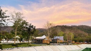 A resort with a swimming pool, tents, and a hilly backdrop.