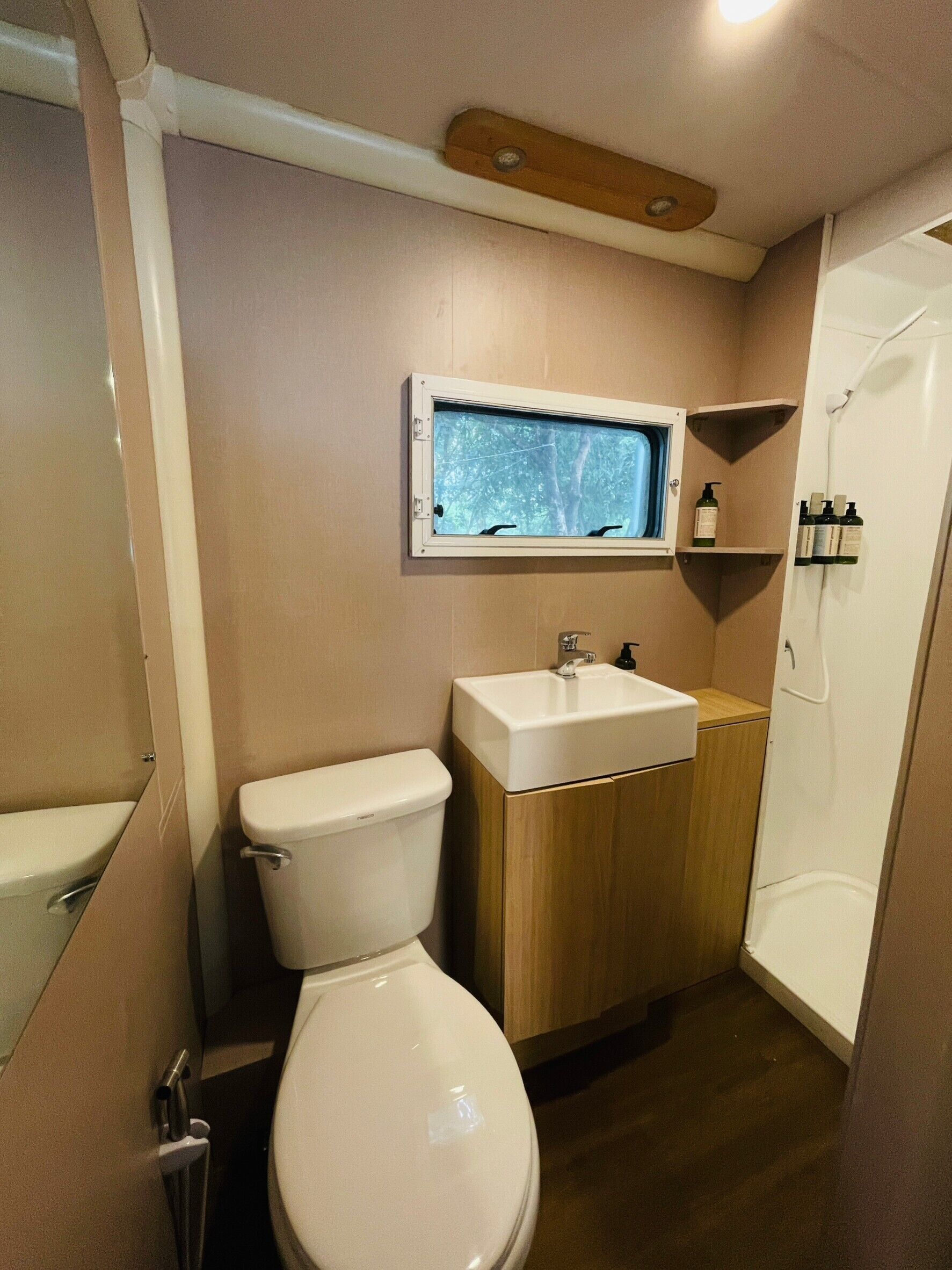 A compact bathroom with a toilet, sink, and window.