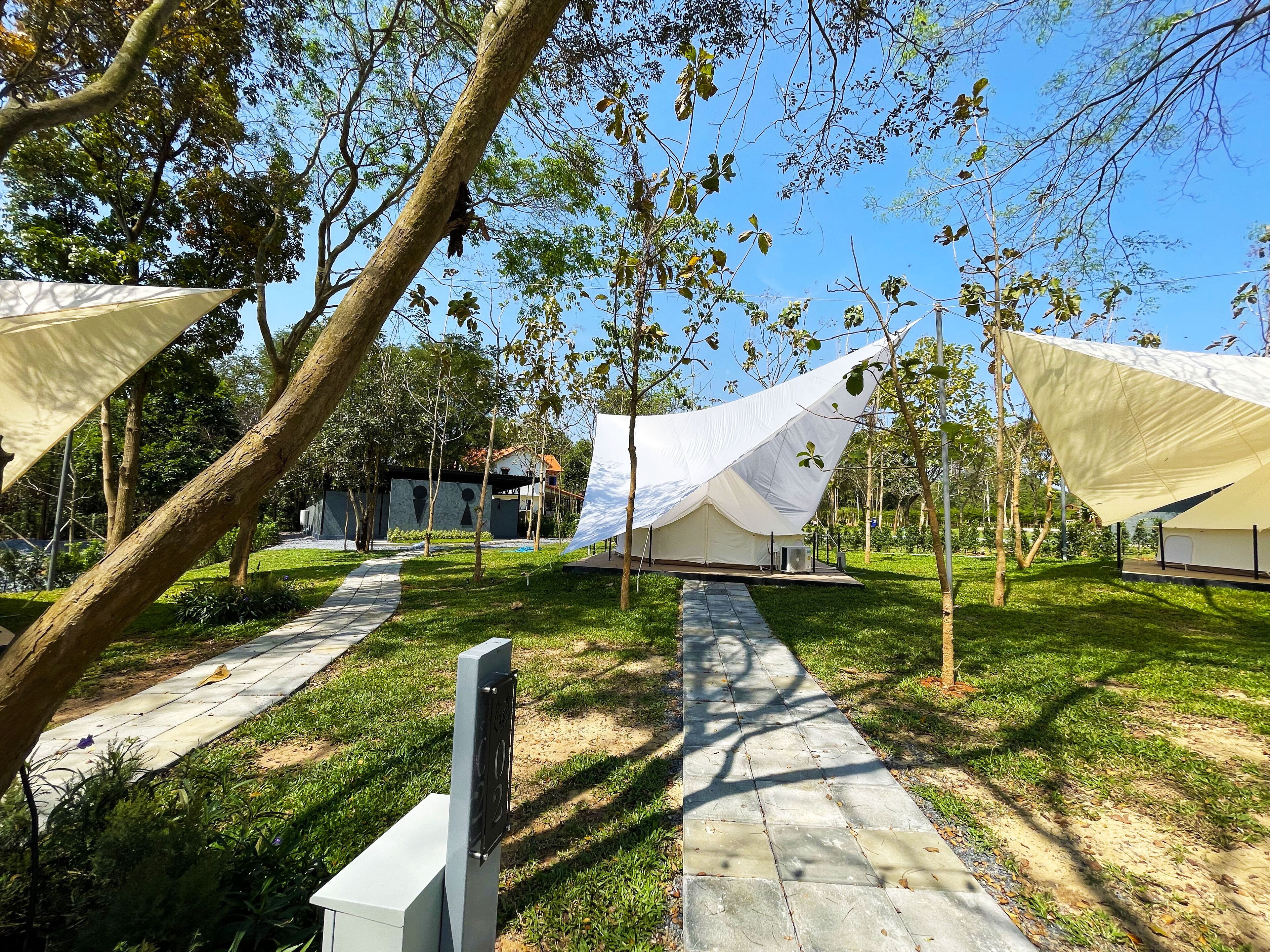A pathway leading to a building with a modern design, surrounded by trees and a clear sky.