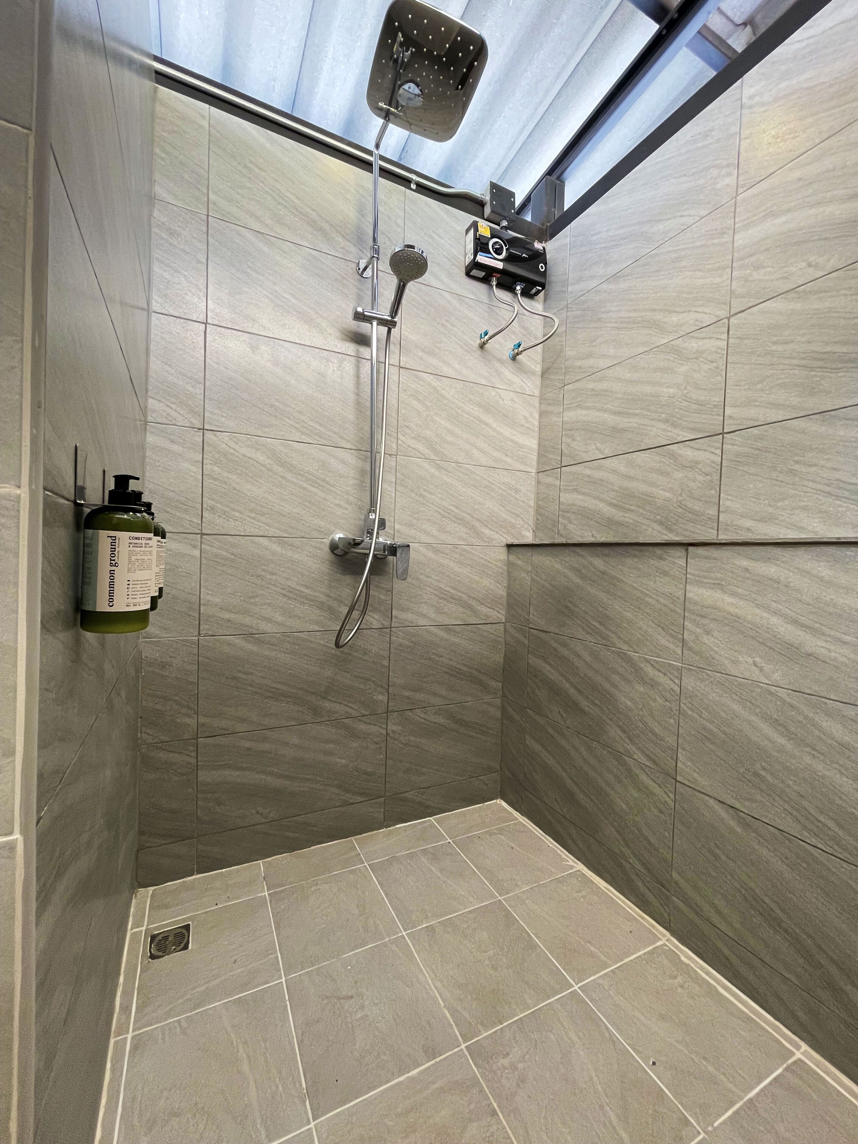 A modern shower area with a handheld showerhead, a wall-mounted faucet, and a handheld showerhead.