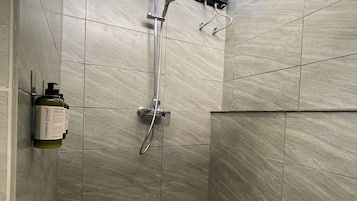 A modern shower area with a handheld showerhead, a wall-mounted faucet, and a handheld showerhead.