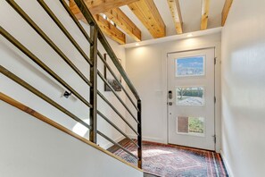 A staircase with wooden beams and metal railings leading to a door with two windows.