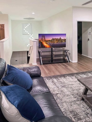 Een moderne woonkamer met een leren bank, een televisie op een dressoir en een kamerbreed tapijt met dessin.