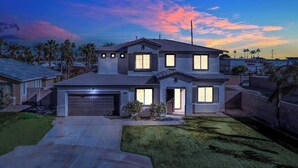 A two-story house with a garage, a well-maintained lawn, and a sunset sky. - Moon Palace • Desert Oasis with Private Pool & Spa (Indio)