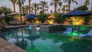 A swimming pool with lounge chairs and umbrellas, surrounded by palm trees. - Moon Palace • Desert Oasis with Private Pool & Spa (Indio)