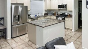 A modern kitchen with white cabinets, stainless steel appliances, and a central island. - Moon Palace • Desert Oasis with Private Pool & Spa (Indio)