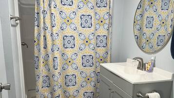 A bathroom with a shower curtain, a sink, a toilet, and a mirror.