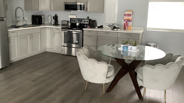 A modern kitchen with white cabinets, stainless steel appliances, and a glass dining table with white chairs. - Plan ahead your next vacation with the at home feeling.  (Yakima)