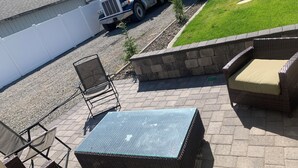 A patio area with a glass-top table, wicker chairs, and a small brick wall. - Plan ahead your next vacation with the at home feeling.  (Yakima)