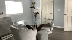 A dining area with a round glass table, white upholstered chairs, and a vase with flowers. - Plan ahead your next vacation with the at home feeling.  (Yakima)