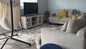A living room with a sofa, a hanging chair, a TV, and a plant. - Plan ahead your next vacation with the at home feeling.  (Yakima)