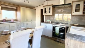 Une cuisine compacte avec des meubles blancs, une table à manger dressée avec des assiettes et des verres, et un four encastré.
