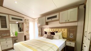 Une chambre à coucher avec un grand lit, une table de chevet, une commode, un miroir et des placards intégrés.