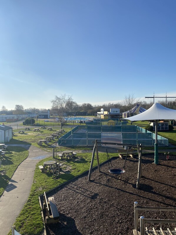 A playground with green structures, picnic tables, and a covered area. - Pet-Friendly 3-Bed Lodge for 8, Tattershall Lakes (Lincoln)