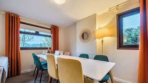 Une chambre d’hôtel équipée d’une table à manger, de chaises, d’une lampe, d’un miroir et offrant une vue sur l’extérieur.