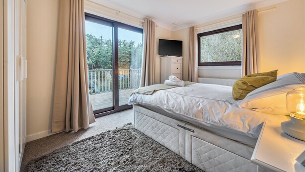 Une chambre à coucher avec un lit, une télévision, une fenêtre et un balcon.