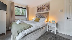 Une chambre à coucher avec un lit, une table de chevet, une lampe et une œuvre d’art accrochée au mur.