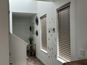 A hallway with a door, a potted plant, and decorative wall art.