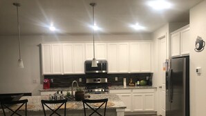 A modern kitchen with white cabinets, stainless steel appliances, and a granite countertop.