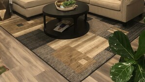A living room with a beige sectional sofa, a round coffee table, and a ceiling fan.