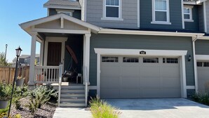 A two-story house with a garage, a covered porch, and a small front yard with plants.